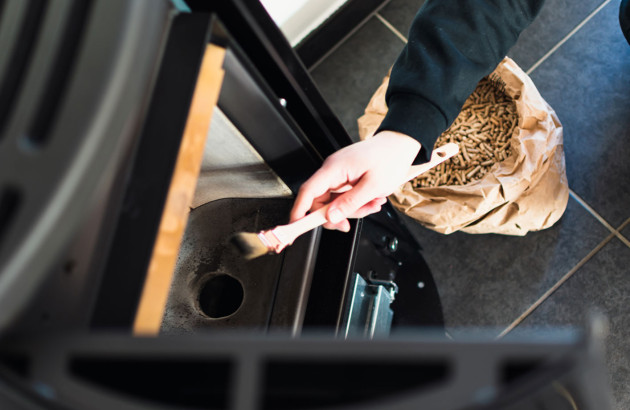 Personne qui nettoie l'intérieur de son poêle à bois avec une brosse