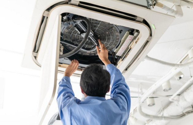 Entretien d’une climatisation cassette au plafond par un technicien pour nettoyer le ventilateur et assurer un air sain.