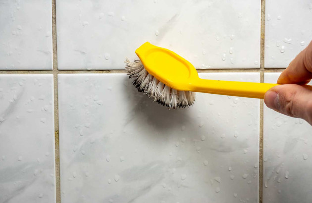 Personne qui nettoie des joints de carrelage avec une brosse