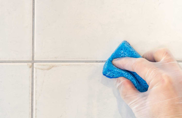 Personne qui nettoie des joints de carrelage avec une éponge