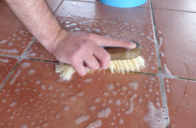 Homme qui nettoie ses joints de carrelage avec une éponge et du savon