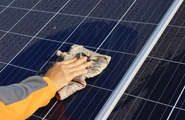Personne qui nettoie un panneau solaire avec un chiffon