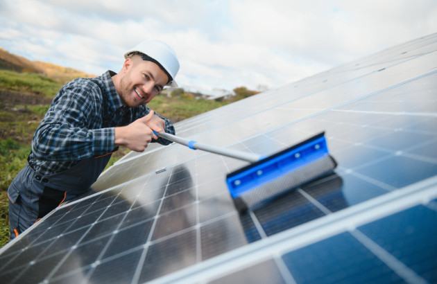 Homme qui nettoie son installation de panneaux solaires