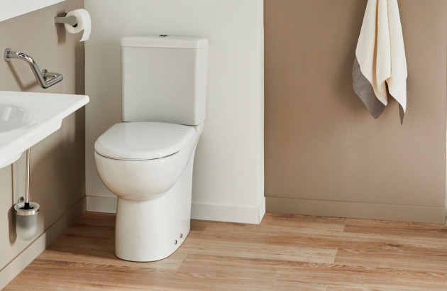 Toilettes PMR sur pied installées près d’un lave-mains avec accessoires adaptés.