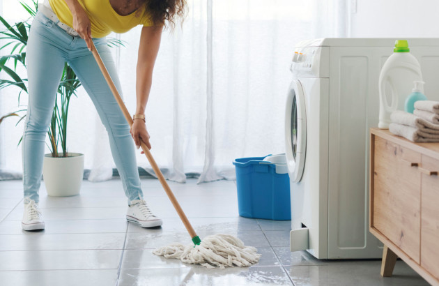 Femme qui nettoie le carrelage de sa buanderie