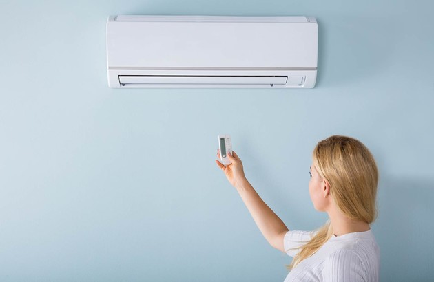 femme réglant sa climatisation avec une télécommande