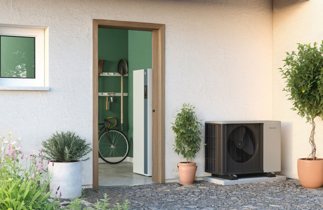 Unité extérieure de pompe à chaleur posée proche d'une porte d'entrée de maison