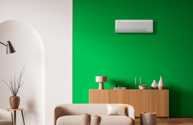 Climatisation murale discrète intégrée dans un salon élégant aux tons neutres et verts.