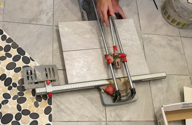 Homme qui découpe des carreaux de carrelage dans une salle de bains