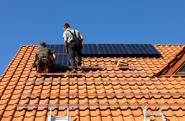 Ouvriers qui installent des panneaux solaires sur des tuiles romanes