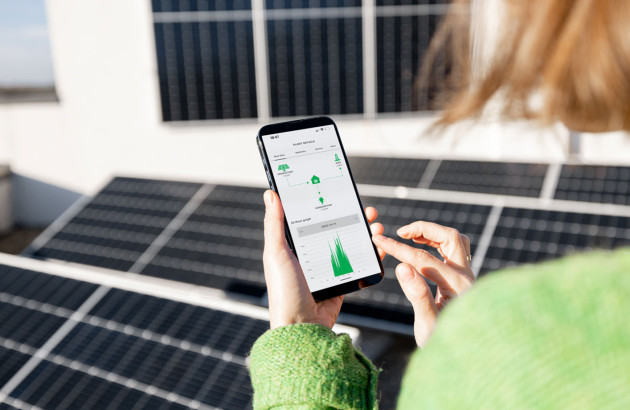 Femme qui contrôle la production de ses panneaux solaires depuis son téléphone