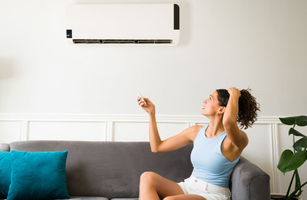 Femme qui s'inquiète en essayant de faire fonctionner sa climatisation