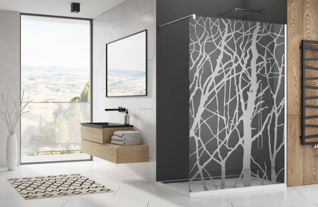 Douche ouverte avec paroi en verre décorée de motifs graphiques blancs dans une salle de bains moderne.