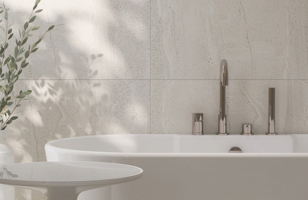 Détail d’une baignoire avec robinetterie moderne devant un mur carrelé clair.