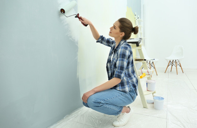 Femme qui peint un mur avec de la peinture blanche