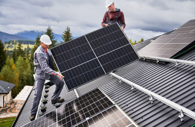 Artisans qui installent des panneaux solaires sur le toit d'une maison