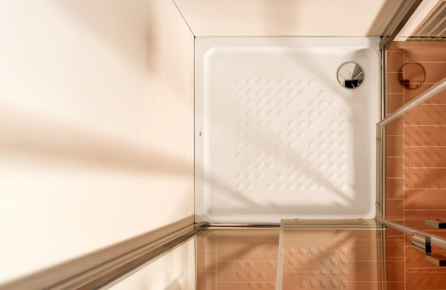 Petit receveur de douche blanc avec surface antidérapante et évacuation ronde.