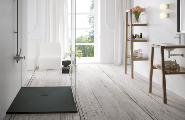 Receveur de douche noir extra-plat intégré dans une salle de bains blanche et épurée.
