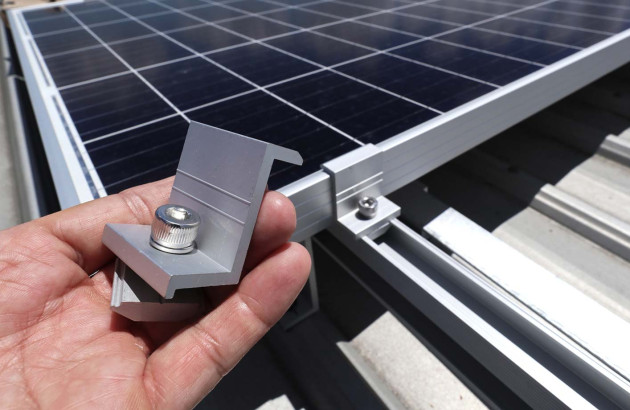 Personne qui tient une pièce de fixation d'un rail de panneau solaire