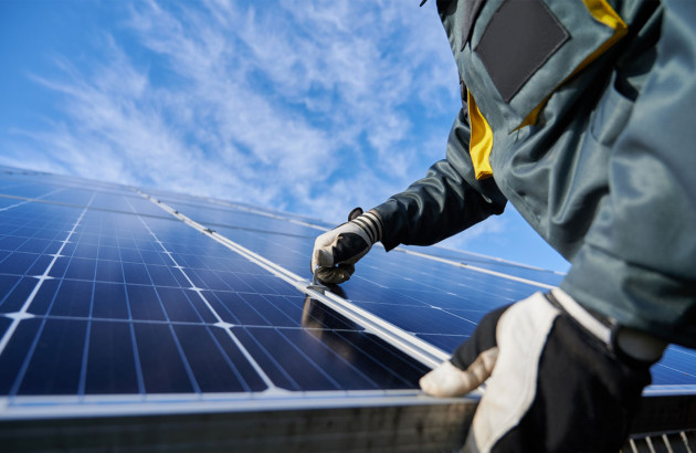 Technicien vérifiant la fixation d’un panneau solaire photovoltaïque.