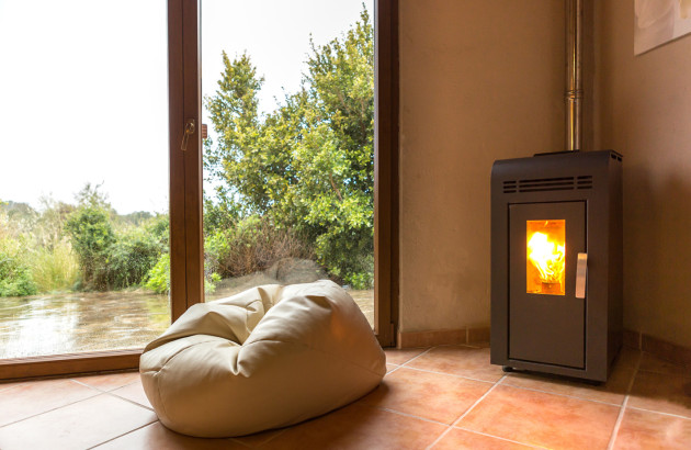 poele à bois dans le coin d'une habitation avec un pouf devant
