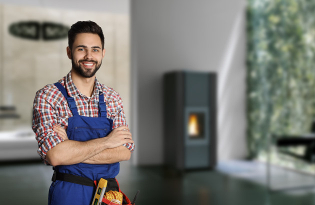 Installateur chauffage devant un poêle à bois