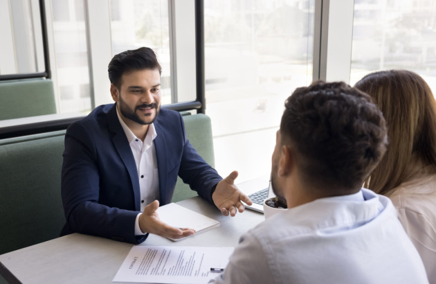 Conseiller échangeant avec un couple autour d’un dossier.