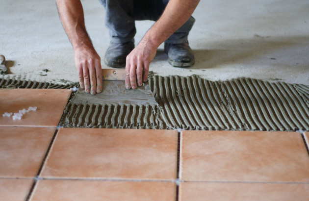Homme qui pose des carreaux de carrelage ocre