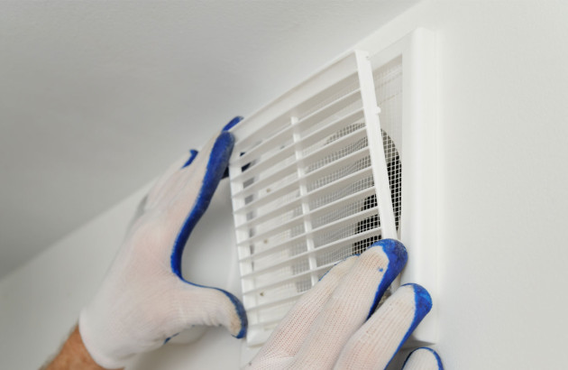 Personne qui pose une grille de ventilation