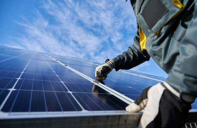 Ouvrier qui pose un panneau solaire sur un toit