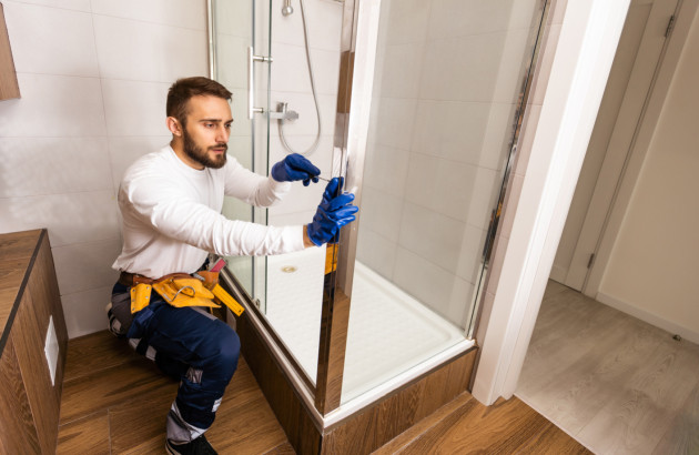 Montage d’une paroi de douche après installation du receveur dans une salle de bains.