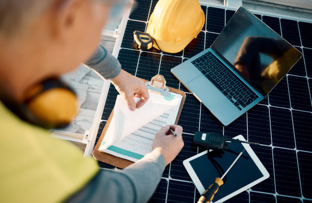 Professionnel contrôlant une installation de panneaux solaires avec du matériel de diagnostic.