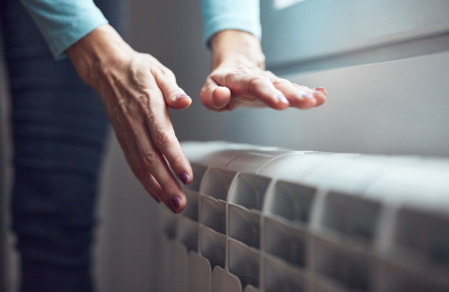 Personne qui place ses mains au dessus du radiateur pour en ressentir la chaleur