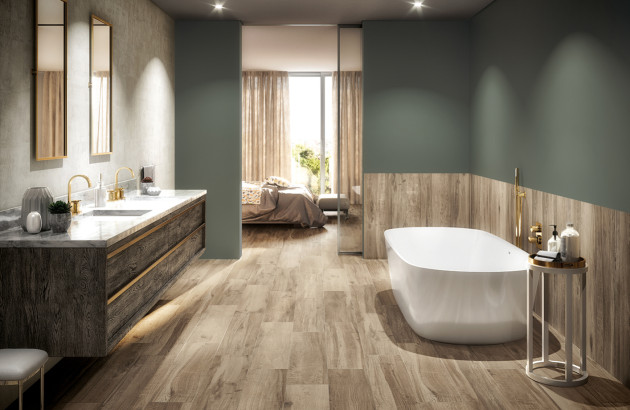Salle de bains élégante avec carrelage imitation bois, baignoire îlot et meuble double vasque moderne.