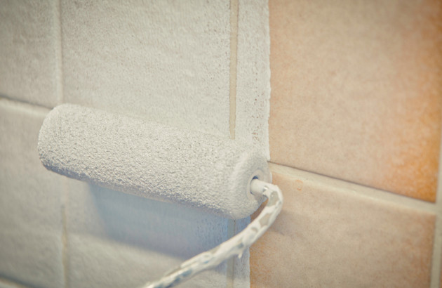 Rouleau de peinture blanche qui peint un mur de carrelage