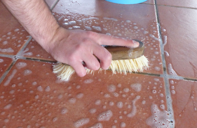 Homme qui nettoie des joints de carrelage avec une brosse à poils 