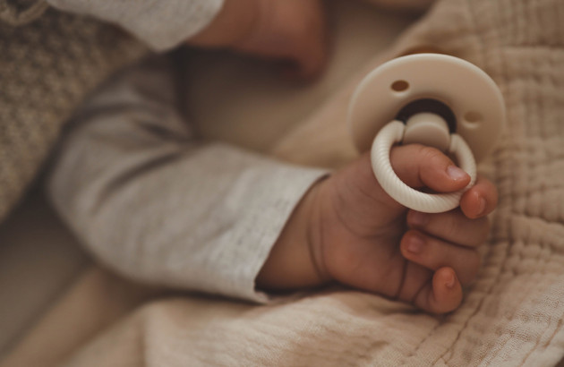 main de bébé qui tient une tétine en train de dormir