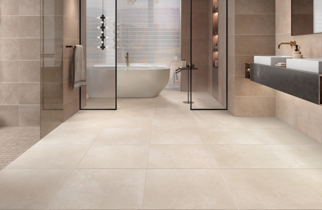 Grande salle de bains avec du carrelage beige effet pierre au sol et sur les murs