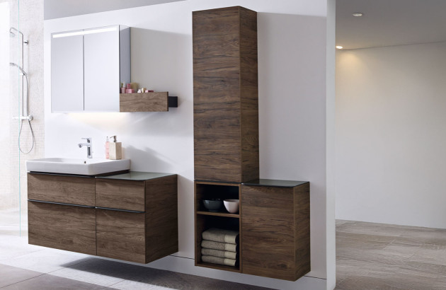 Ensemble de meubles de salle de bains en finition bois foncé avec colonne haute, rangements ouverts et miroir avec éclairage intégré.