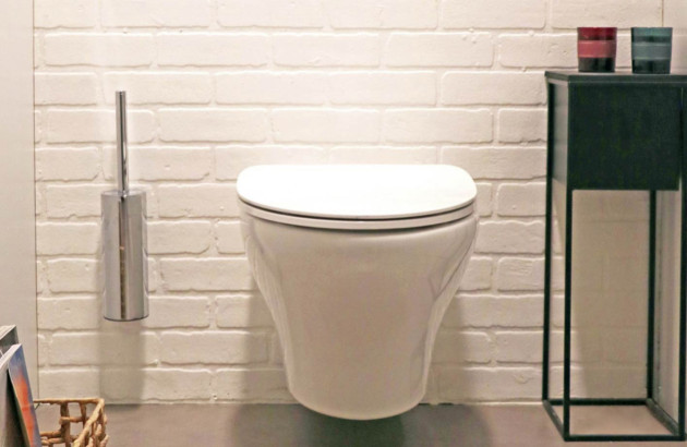 WC suspendu blanc aux lignes arrondies installé dans un espace aux tons vert pastel.