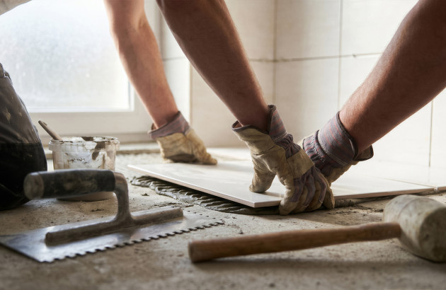 Installation de carrelage intérieur avec outils de carreleur et colle adaptée au support.