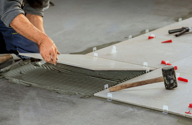 Homme qui pose des carreaux de carrelage sur du mortier colle au sol