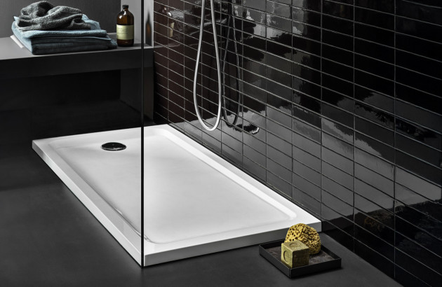 Bac de douche blanc installé avec paroi vitrée et carrelage mural noir brillant