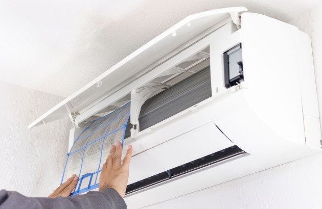 Personne qui intervient sur le filtre d'un climatiseur