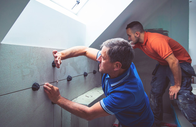 Artisans qui installent des carreaux de carrelage muraux dans une salle de bains