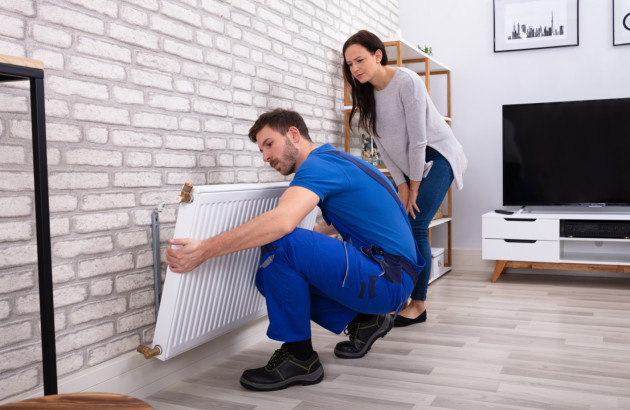 Artisan qui installe un radiateur dans une maison d'une particulière