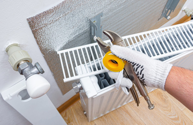 Homme qui tient des outils au dessus d'un radiateur