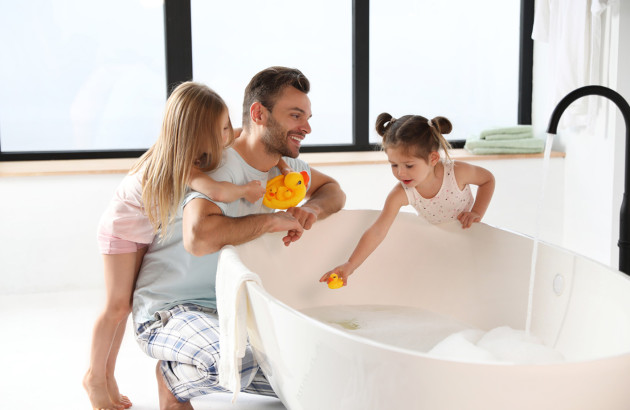 Père de famille qui passe du bon temps avec ses filles autour d'une baignoire