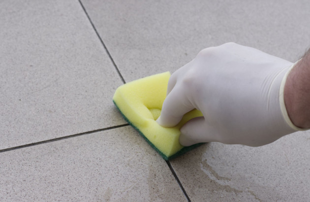 Homme qui passe l'éponge sur les joints de carrelage