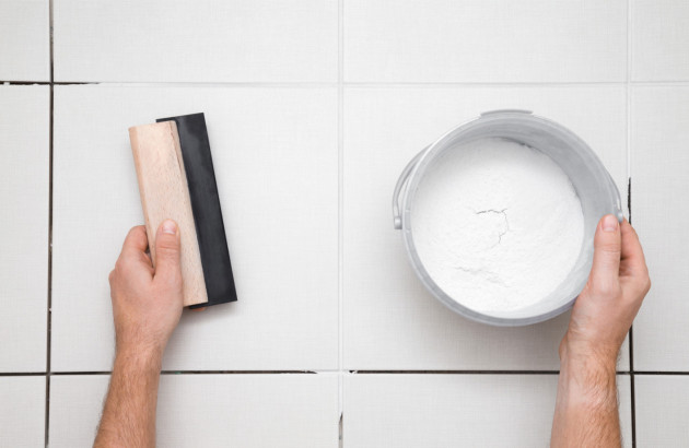Préparation d’un joint de carrelage avec taloche et mortier pour une rénovation étanche.